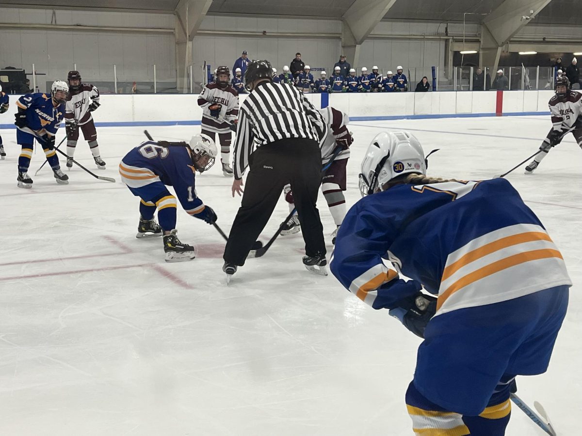 Captains,  junior; Daniela Parise (furthest on the left), senior; Isla Wilson (center), and senior; Katie Malley (closest to the screen), setting up for the face off against Dedham