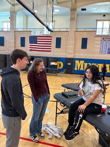 Seniors James Saulnier and Meghan Savilia laugh with Nicolli Bengolea after she gives blood. 