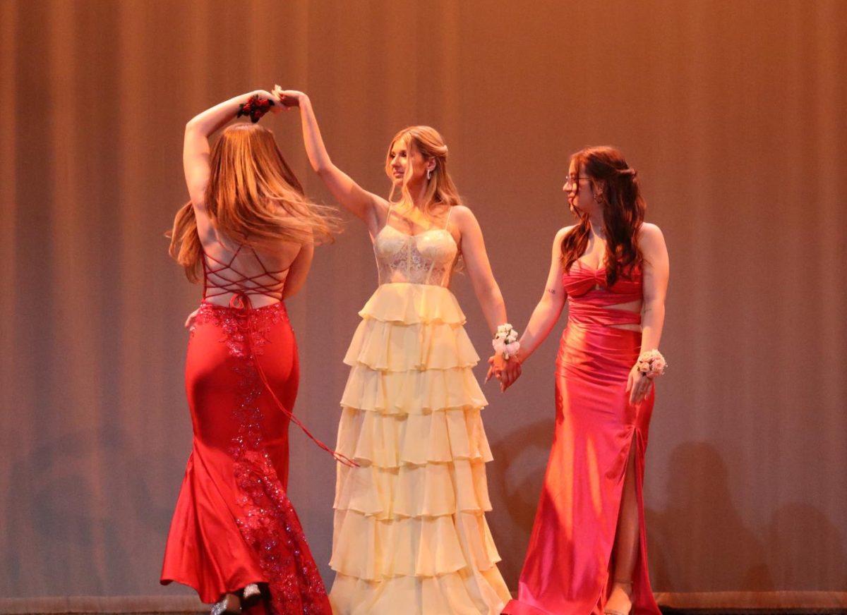 Kendra Berg, Tori Roderick, and Ella Gearty twirling across the runway