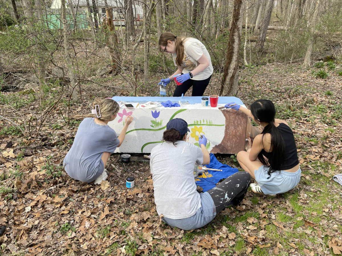 Volunteers paint a cement block at the Block Painting Earth Week Event on the Germany Brook Trail